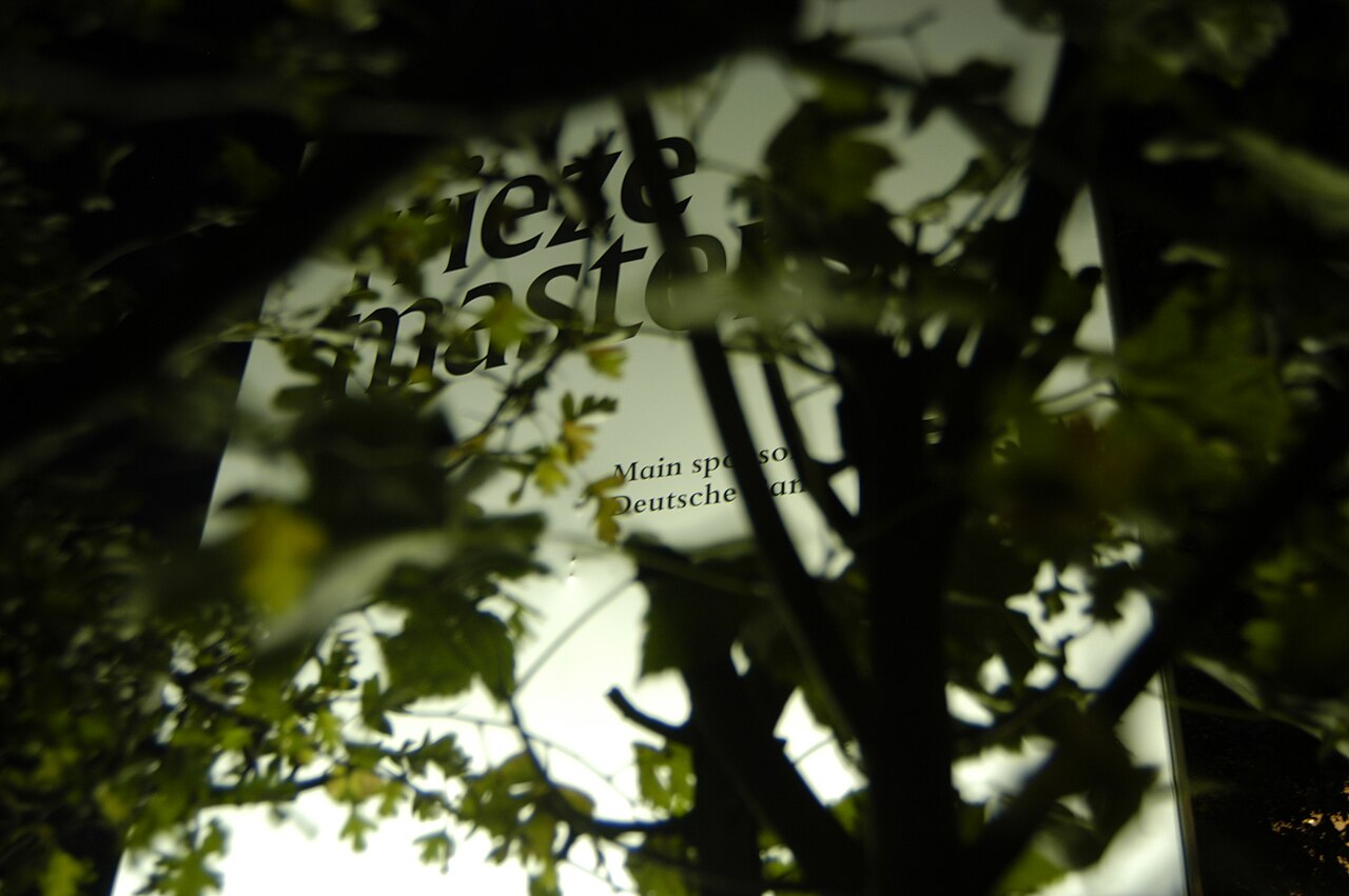 A backlit Frieze Masters sign seen through trees in The Regent's Park.